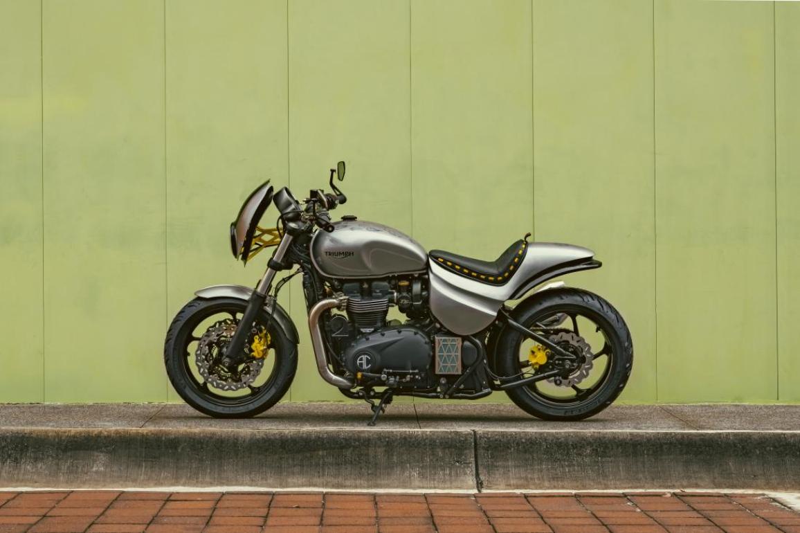 Η Triumph Originals 2025 ξεκίνησε με την παρουσίαση συμμετοχών από οκτώ χώρες και των κριτών που θα επιλέξουν την πιο πρωτότυπη custom Bonneville Με θέμα το “Icons of British Originality”, κάθε ομάδα της Triumph συνεργάστηκε με έναν τοπικό custom builder για να δημιουργήσει μια μοτοσυκλέτα που αποτυπώνει την πολιτισμική επιρροή της Βρετανίας μέσα από το δικό της πρίσμα. Η βάση όλων των συμμετοχών είναι μοντέλα από τη σύγχρονη σειρά Bonneville. Ακολουθούν οι μοτοσυκλέτες που διαγωνίζονται για την διάκριση: ΗΠΑ – Βασισμένη σε Bonneville T120, η συμμετοχή των ΗΠΑ είναι εμπνευσμένη από την αγωνιστική κουλτούρα της Indianapolis και την αγωνιστική κληρονομιά της Triumph. Η έντονη μπλε και κίτρινη σχεδίαση με vintage λογότυπα δημιουργήθηκε από τον Bret Johnson της Triumph Indianapolis με τη συμβολή του Victor Tulli. Μεξικό – Η Aftercycles σχεδίασε μια Bonneville Bobber εμπνευσμένη από την αγγλική pop κουλτούρα. Ξεχωρίζει η σέλα με την κίτρινη ραφή, φόρος τιμής στο brand Dr. Martens, και το custom σήμα του γκαζιού «Platform 9¾» ως αναφορά στον Harry Potter. Βραζιλία – Το Gaijin είναι ένα σκοτεινό, μινιμαλιστικό café racer βασισμένο σε Speed Twin 1200, σχεδιασμένο από τη Shibuya στο Σάο Πάολο. Χειροποίητες λεπτομέρειες, όπως ο διακριτικός σχεδιασμός στο ρεζερβουάρ και η minimal ουρά, αποπνέουν αίσθηση ταχύτητας ακόμα και σε στάση. Γαλλία – Η FCR Original τίμησε τον παράλληλο δικύλινδρο κινητήρα της Triumph με το Hail to the Twin, βασισμένο στο Speed Twin 1200 RS. Νέα σχεδίαση πίσω μέρους, ειδική μπροστινή ζάντα και custom βαφή με φύλλα χρυσού και χαλκού αναδεικνύουν τις γραμμές της μοτοσυκλέτας. Καναδάς – Η in-house ομάδα της Motos Illimitées παρουσίασε μια Speed Twin 1200 RS με ειδική εξάτμιση από ανοξείδωτο ατσάλι, χαμηλό τιμόνι και custom βαφή σε γραφίτη και χρυσό με χειροποίητα pinstripes και ένα περασμένο λογότυπο της Triumph. Ιταλία – Ο Giuseppe Carucci της South Garage Motor Co παρουσίασε μια αριστοκρατική Bonneville Bobber, εμπνευσμένη από τις Speed Twins των δεκαετιών ’30-’40. Η μοτοσυκλέτα φέρει ριζικά επανασχ