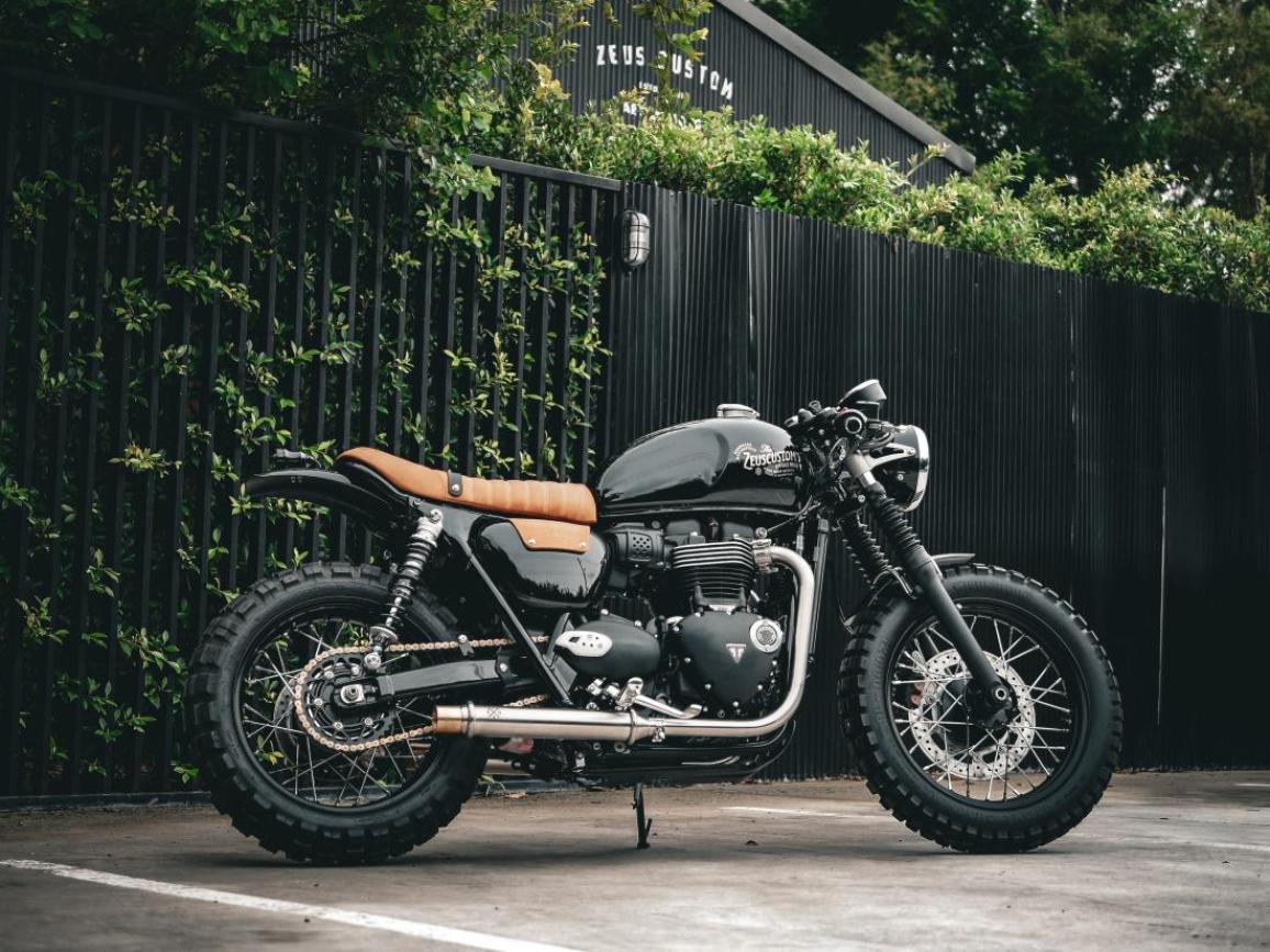 Η Triumph Originals 2025 ξεκίνησε με την παρουσίαση συμμετοχών από οκτώ χώρες και των κριτών που θα επιλέξουν την πιο πρωτότυπη custom Bonneville Με θέμα το “Icons of British Originality”, κάθε ομάδα της Triumph συνεργάστηκε με έναν τοπικό custom builder για να δημιουργήσει μια μοτοσυκλέτα που αποτυπώνει την πολιτισμική επιρροή της Βρετανίας μέσα από το δικό της πρίσμα. Η βάση όλων των συμμετοχών είναι μοντέλα από τη σύγχρονη σειρά Bonneville. Ακολουθούν οι μοτοσυκλέτες που διαγωνίζονται για την διάκριση: ΗΠΑ – Βασισμένη σε Bonneville T120, η συμμετοχή των ΗΠΑ είναι εμπνευσμένη από την αγωνιστική κουλτούρα της Indianapolis και την αγωνιστική κληρονομιά της Triumph. Η έντονη μπλε και κίτρινη σχεδίαση με vintage λογότυπα δημιουργήθηκε από τον Bret Johnson της Triumph Indianapolis με τη συμβολή του Victor Tulli. Μεξικό – Η Aftercycles σχεδίασε μια Bonneville Bobber εμπνευσμένη από την αγγλική pop κουλτούρα. Ξεχωρίζει η σέλα με την κίτρινη ραφή, φόρος τιμής στο brand Dr. Martens, και το custom σήμα του γκαζιού «Platform 9¾» ως αναφορά στον Harry Potter. Βραζιλία – Το Gaijin είναι ένα σκοτεινό, μινιμαλιστικό café racer βασισμένο σε Speed Twin 1200, σχεδιασμένο από τη Shibuya στο Σάο Πάολο. Χειροποίητες λεπτομέρειες, όπως ο διακριτικός σχεδιασμός στο ρεζερβουάρ και η minimal ουρά, αποπνέουν αίσθηση ταχύτητας ακόμα και σε στάση. Γαλλία – Η FCR Original τίμησε τον παράλληλο δικύλινδρο κινητήρα της Triumph με το Hail to the Twin, βασισμένο στο Speed Twin 1200 RS. Νέα σχεδίαση πίσω μέρους, ειδική μπροστινή ζάντα και custom βαφή με φύλλα χρυσού και χαλκού αναδεικνύουν τις γραμμές της μοτοσυκλέτας. Καναδάς – Η in-house ομάδα της Motos Illimitées παρουσίασε μια Speed Twin 1200 RS με ειδική εξάτμιση από ανοξείδωτο ατσάλι, χαμηλό τιμόνι και custom βαφή σε γραφίτη και χρυσό με χειροποίητα pinstripes και ένα περασμένο λογότυπο της Triumph. Ιταλία – Ο Giuseppe Carucci της South Garage Motor Co παρουσίασε μια αριστοκρατική Bonneville Bobber, εμπνευσμένη από τις Speed Twins των δεκαετιών ’30-’40. Η μοτοσυκλέτα φέρει ριζικά επανασχ